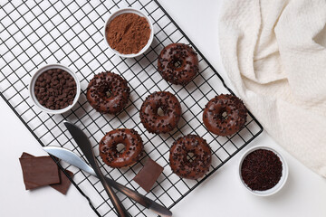 Preparation of chocolate donuts on a light background.