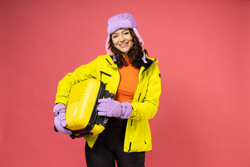 A woman in a warm ski suit with a suitcase.