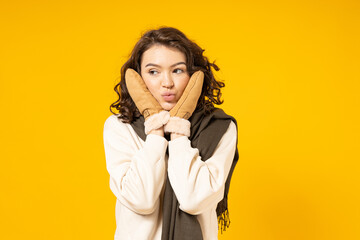 Beautiful girl in warm, winter clothes on a yellow background.