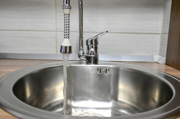 Drinking water flows from the tap into the sink. Drinking water in the tap.