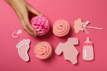 Cupcakes, paper decorations and hand on pink background, top view
