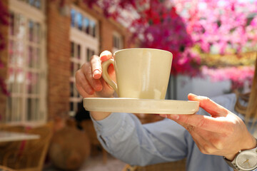 Cup in female hands in outdoor cafe, close up