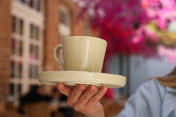Cup in female hand in outdoor cafe, close up