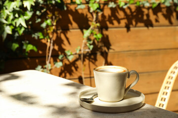 Beige cup with coffee on table outdoors, space for text