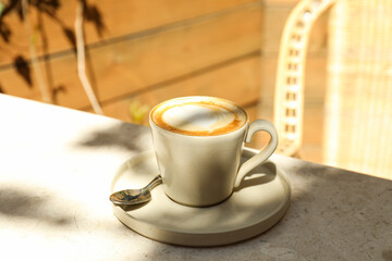 Beige cup with coffee on table in cafe, outdoors