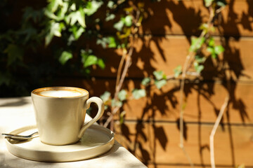 Beige cup with coffee on table outdoors, space for text