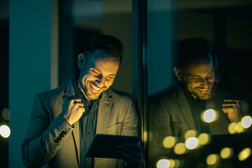 Smiling young businessman standing in his office and working with a digital tablet