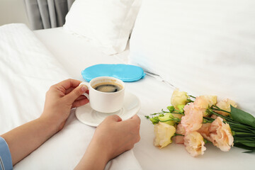 Sleeping mask, coffee and flowers on the bed