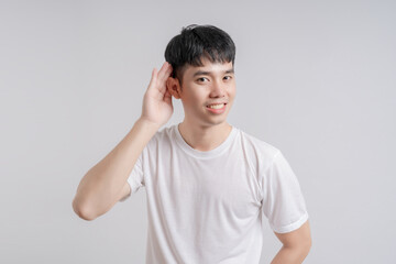 Handsome young man pretends to be a spy covers his ears with his hands