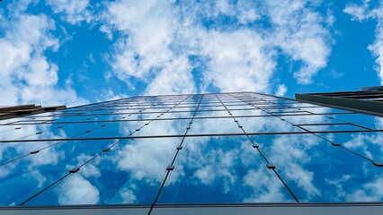 Fototapeta premium building Looking up tall glass and steel high rise. Cloudy sky