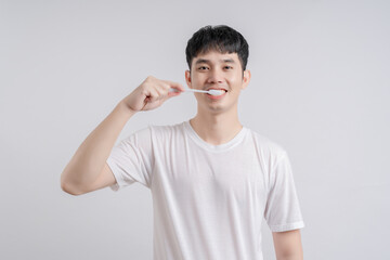 Handsome young man smiles happily and holding toothbrush.