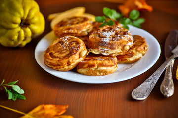 Cooked fried round pancakes with quince filling on a wooden table