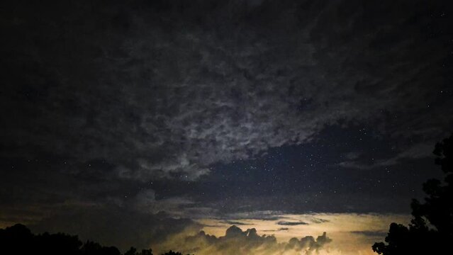 Late night to early morning time lapse of clouds moving against starry sky