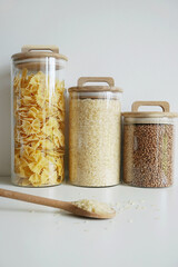 Transparent containers with pasta, rice and buckwheat on a white background