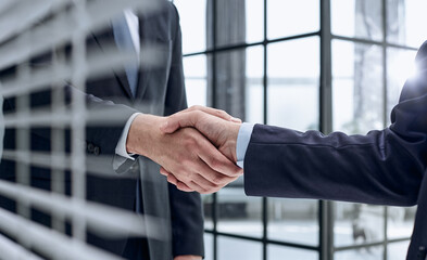 executives shaking hands in front of their manager and a colleague