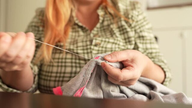 Woman sewing up hole in clothes, handmade