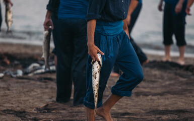 Unrecognizable person walking away with selected fish near blurred seawater