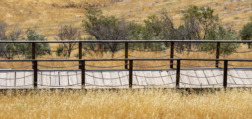 Wooden fence bridge over meadow and grass. Made of rope ropes. Sidewalk pathway