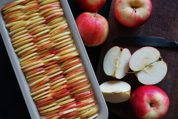 Apple pie next to apples and knife on wooden board