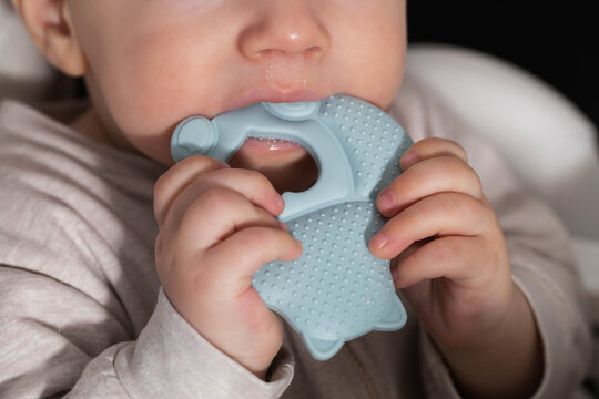 One year old caucasian boy with silicone cooling massager during teething. Itching of gums, massage and salivation during teething in children, stomatological