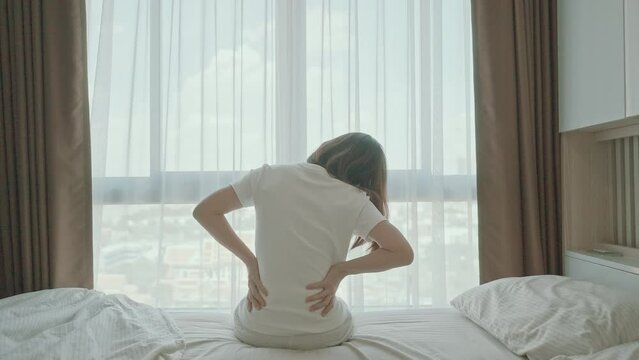 woman having back body ache during sitting on bed at home. adult female with muscle pain after Waking up due to Piriformis Syndrome, Low Back Pain and Spinal Compression. Health medical concept
