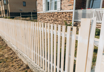 Wooden fence around a beautiful house. fence made of wooden slats. - obrazy, fototapety, plakaty