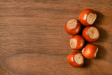 Background with several brown hazelnuts on a wooden backing. Space for text.