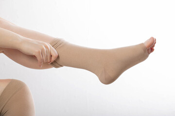 A woman puts on compression stockings for legs with varicose veins. Pain and swelling in the legs,...