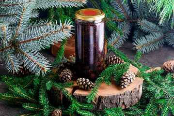 Jam from young pine cones in syrup on a background with pine branches