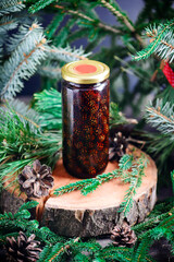 Jam from young pine cones in syrup on a background with pine branches