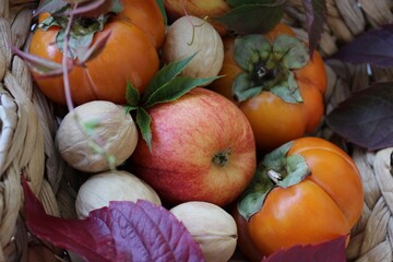 bright background. basket with apples, nuts and persimmons. beautiful background texture. juicy fruits. vitamins
