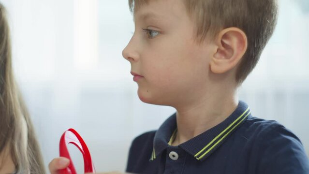 A close-up of a boy who conveniently takes tweezers to perform a task. Colored balls that need to be arranged into a flower. High quality 4k footage