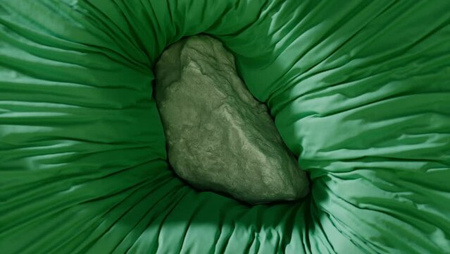 A rock falls into a green fabric