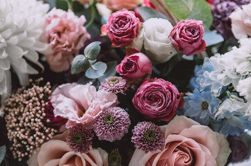 Beautiful bouquet of roses, gypsophila and other different flowers on dark background
