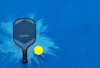 Pickleball tennis racket on the court. Blue background with copy space. Sport court and ball.