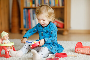 Adorable cute little toddler girl playing with doll. Happy healthy baby child having fun with role...