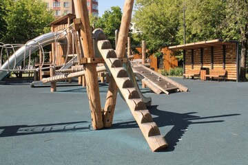 Wooden playground made of natural eco-friendly material in public city park. Modern safety children outdoor equipment. Concept of sustainable lifestyle and ecology. Children rest and games on open air - obrazy, fototapety, plakaty