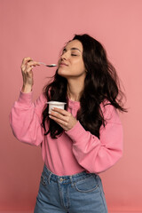Brunette inhaling the yogurt aroma from the spoon in her hand with her eyes closed during the...