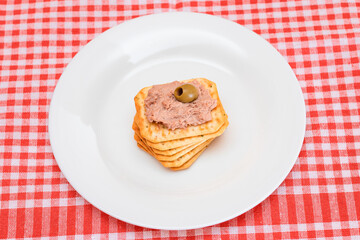 Crispy Salted Cracker with Liver Pate and Olives on White Plate. Easy Snack