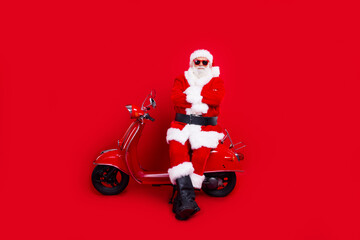 Full length portrait of charismatic aged santa sit bike crossed arms christmas time isolated on red...