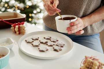 Unrecognizable woman decorating Christmas cookies with a chocolate glaze
