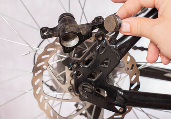 Brake pad in the hand of a bicycle repair and maintenance master. Replacing brake pads with disc brakes. Close-up