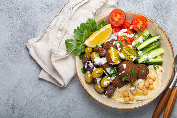 Falafel salad bowl with hummus, vegetables, olives, herbs and yogurt sauce. Vegan lunch plate top...