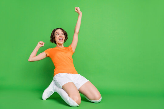 Full body portrait of astonished lady open mouth stand on knees slide look empty space isolated on green color background