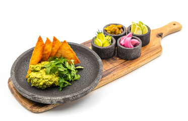 Avocado dip guacamole with crispy tortillas on black stone plate on white background