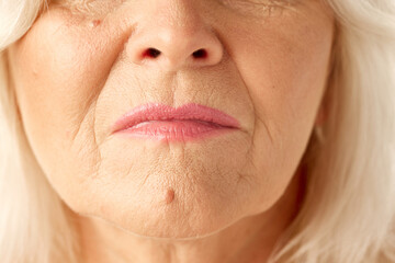 Close-up image of female mouth, lips. Elderly woman with wrinkled face. Natural beauty, keeping healthy skin. Concept of natural beauty, aging process, elderly beauty, cosmetology, skincare