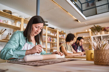 Woman working with clay in a pottery workshop. Craft and hobby concept.