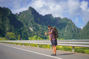 Fototapeta na wymiar Tourist waving hand asking for help on the highway, Hitchhiking on the road, Travel man hitchhiking