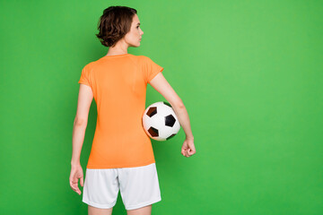Rear portrait of calm person arm hold ball look interested empty space isolated on green color background