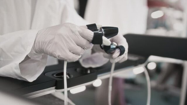A medic girl controls a medical robot Da Vinci. A woman doctor performs an innovative remote operation. A female holds a surgical scalpel control tool in her hands. Cancer treatment in virtual reality